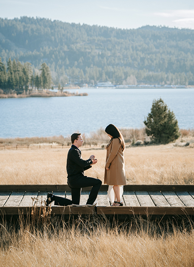 California's best surprise proposal photographer in Big Bear Lake – a groom-to-be on one knee proposing to his partner at a scenic coastal overlook, capturing raw emotion and joy.