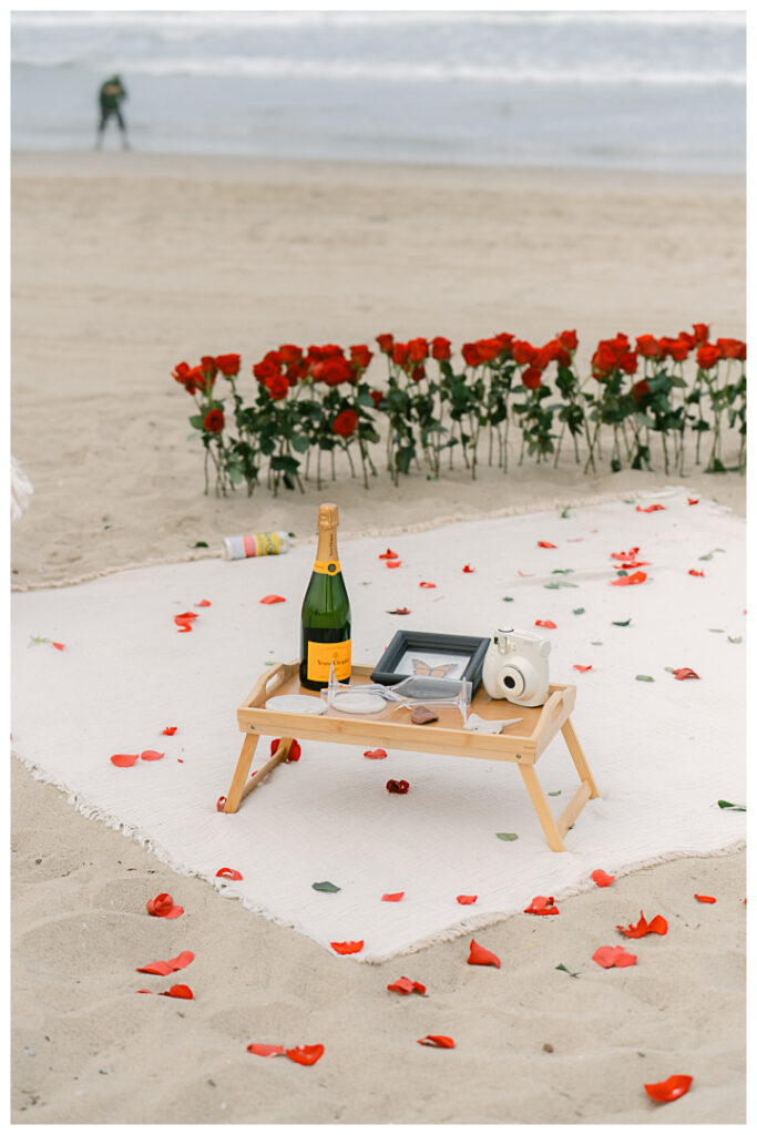 Romantic DIY beach proposal setup with red roses at Venice Beach, California.