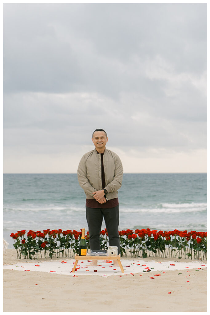 Romantic DIY beach proposal setup with red roses at Venice Beach, California.