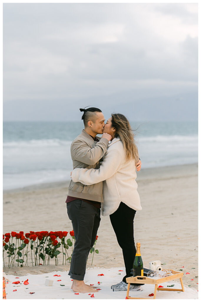 Romantic DIY beach proposal setup with red roses at Venice Beach, California.