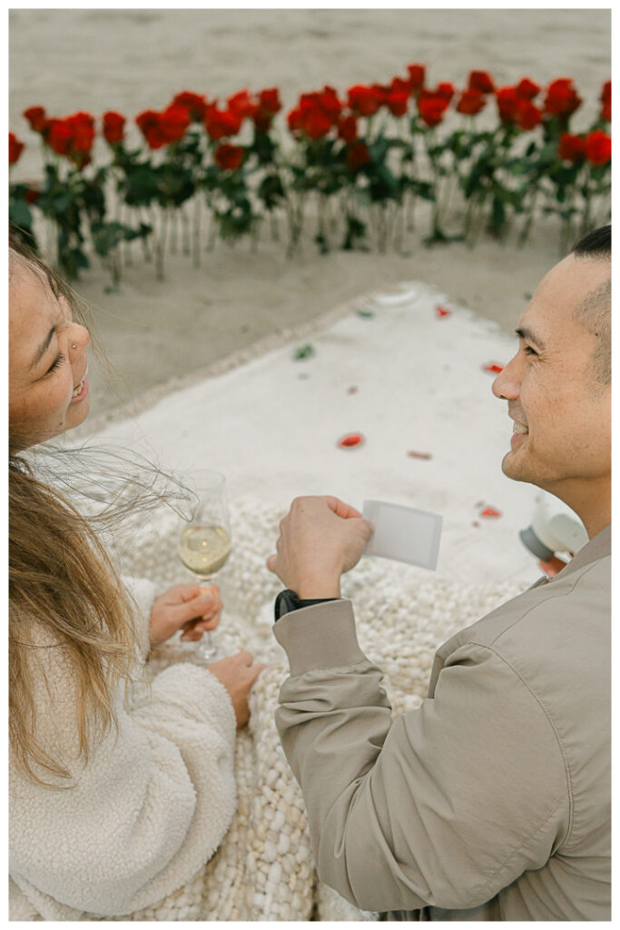 Romantic DIY beach proposal setup with red roses at Venice Beach, California.