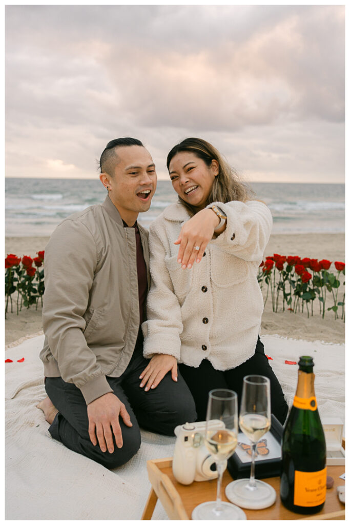 Romantic DIY beach proposal setup with red roses at Venice Beach, California.