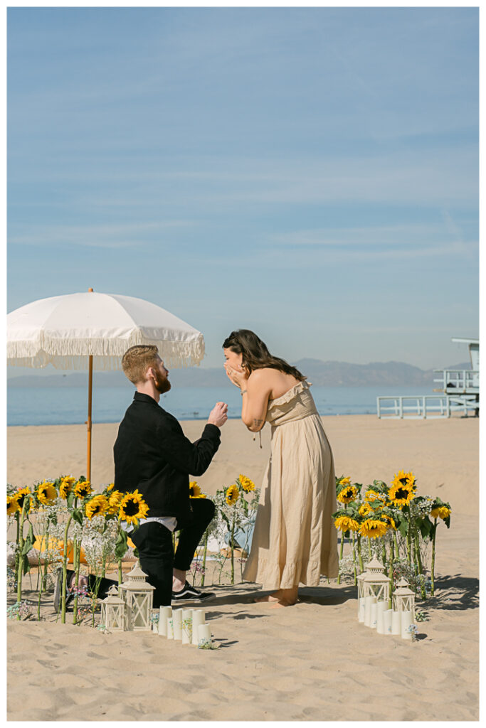 A couple embraces at their beach picnic proposal in Hermosa Beach, Los Angeles.