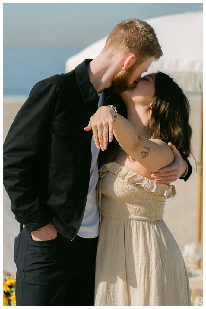 A couple embraces at their beach picnic proposal in Hermosa Beach, Los Angeles.