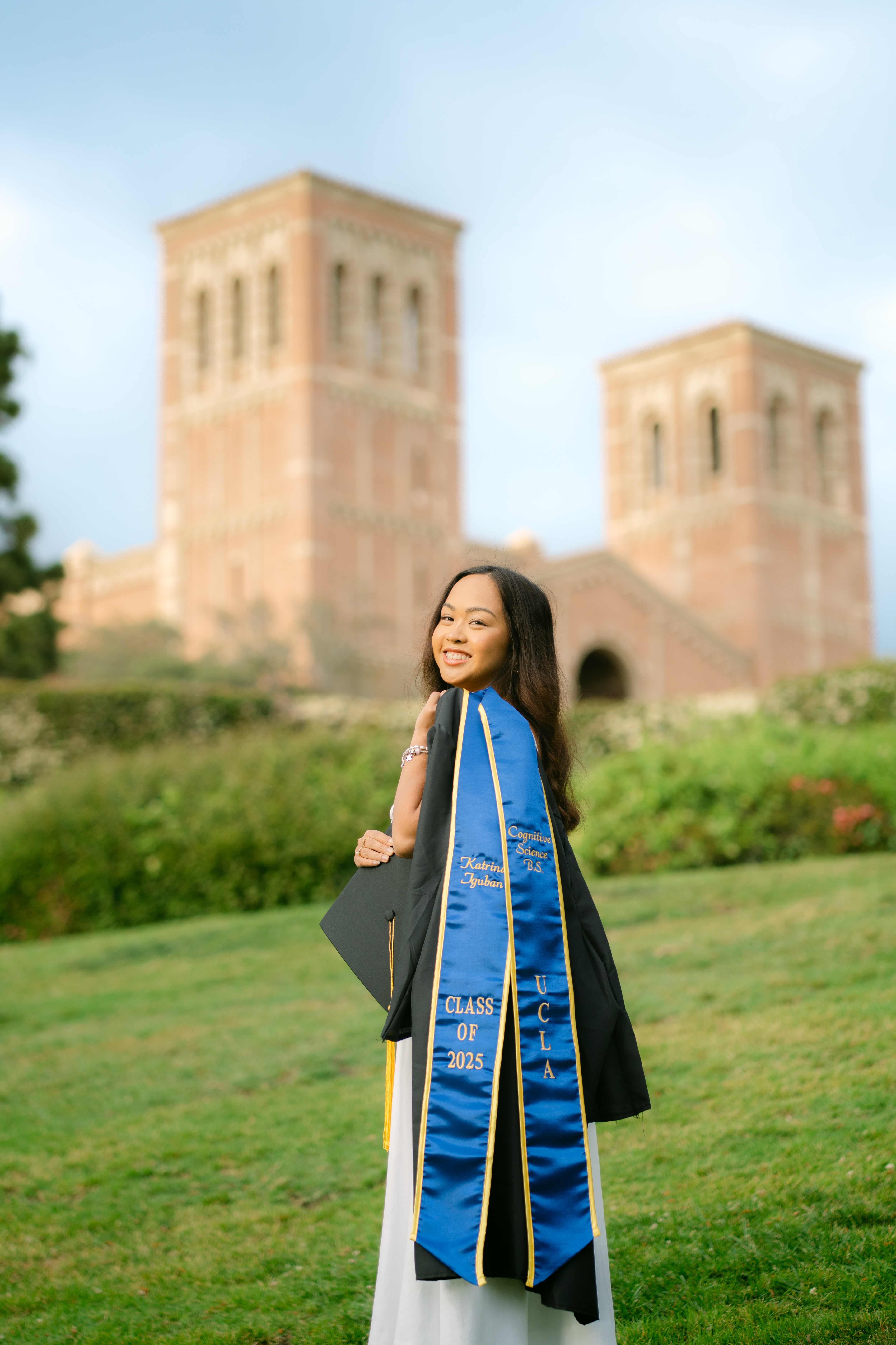 UCLA senior Katrina smiling in cap and gown on campus with her family and friends.