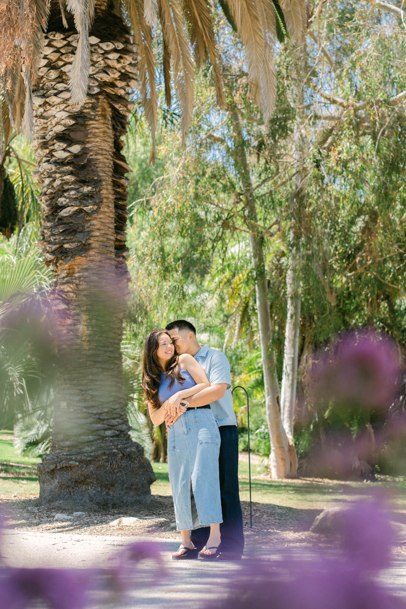 Couple celebrating engagement with a joyful embrace in a meadow