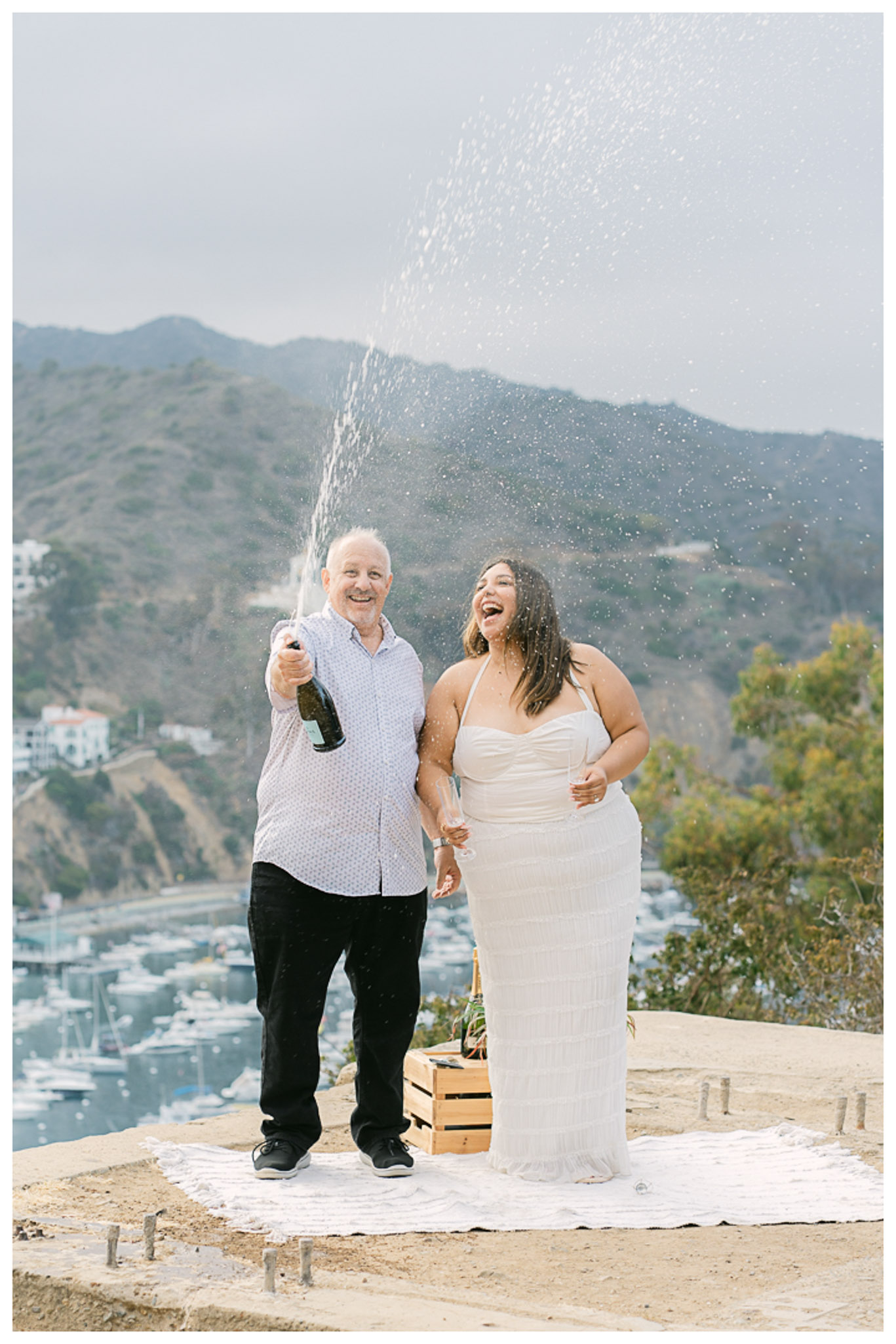 Surprise proposal on Catalina Island with red and white roses and ocean backdrop