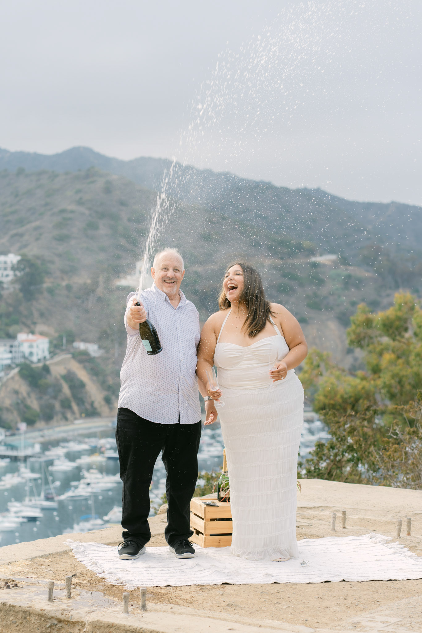 Surprise proposal on Catalina Island with red and white roses and ocean backdrop