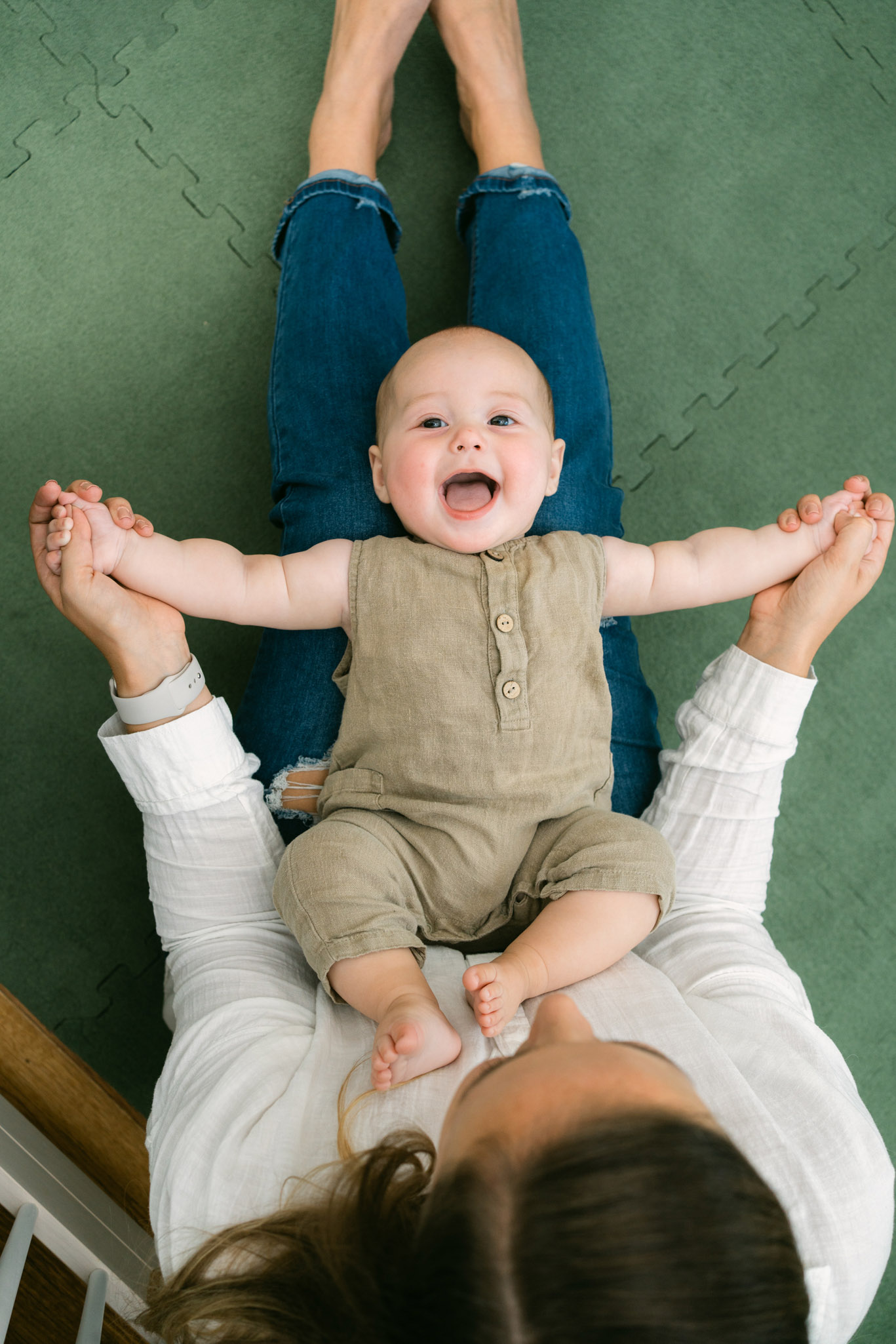 In-home baby milestone photography session with parents in cozy nursery