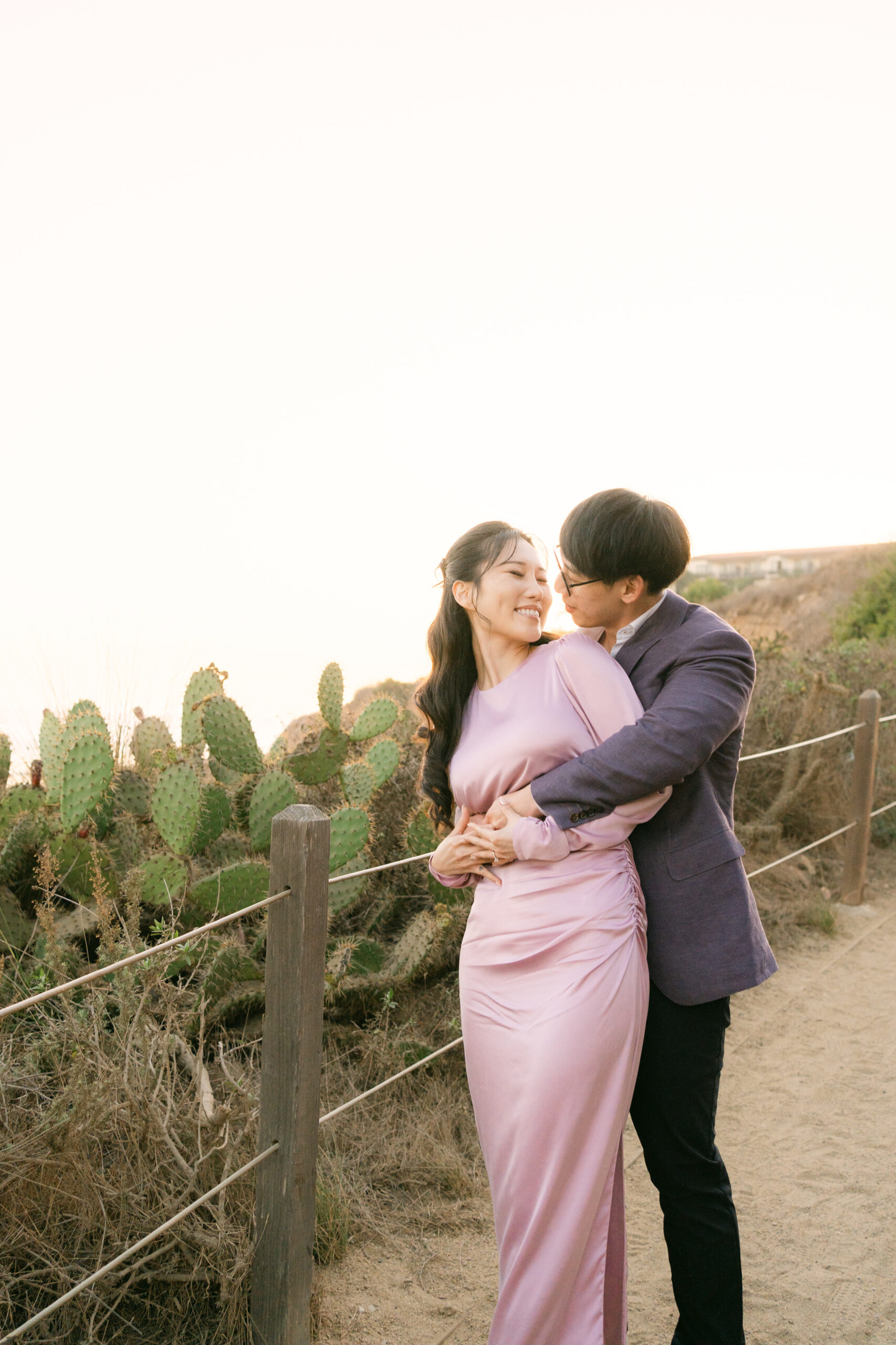 Couple embracing on a Malibu bluff at golden hour during their engagement session