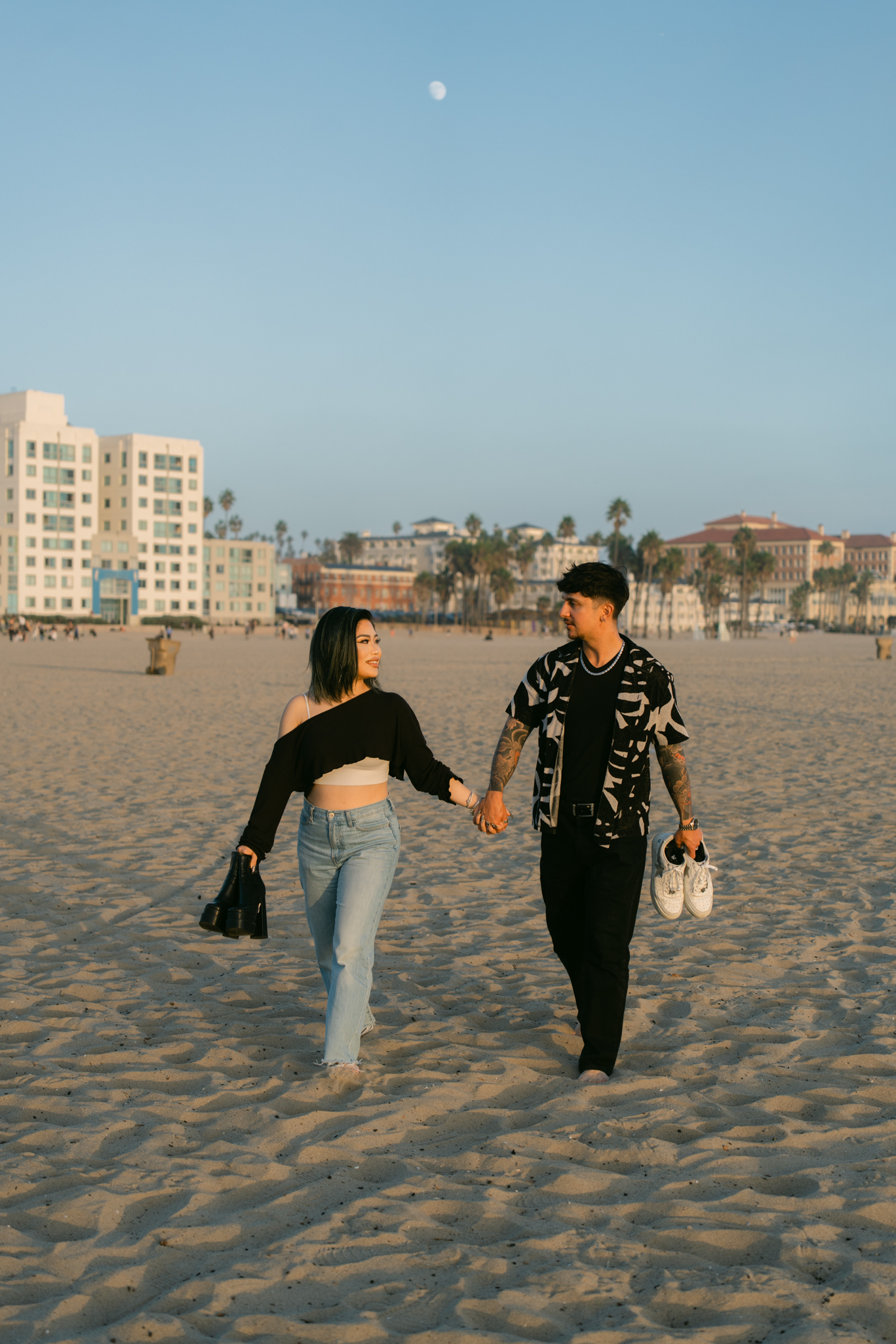 Surprise proposal at Santa Monica Pier at sunset, photographed as the couple walks along the beach